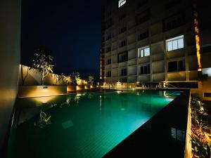 トリバンドラムにあるLuxe Luminar- 1 BHK Apartmentの夜の建物の前のプール