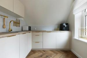 a white kitchen with white cabinets and a window at Elite Apartments Długa Prestige in Gdańsk