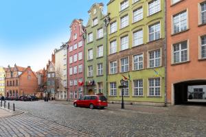 a red car parked in front of a row of buildings at Elite Apartments Długa Prestige in Gdańsk +23 photos