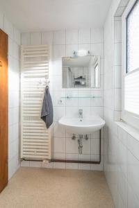 een witte badkamer met een wastafel en een spiegel bij Himmelsrichtung in Norderney