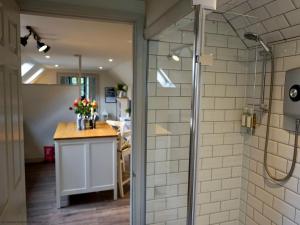 baño con cabina de ducha y cocina en The Barn, en South Cerney