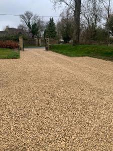a gravel road in a park with trees and grass at The Barn in South Cerney