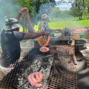 Dois homens estão a cozinhar comida num grelhador. em Livivane Guest House em Simunye