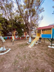 a playground with a slide and a tree at Happy Camp mobilehomes in Camping Apollonia in Plakias