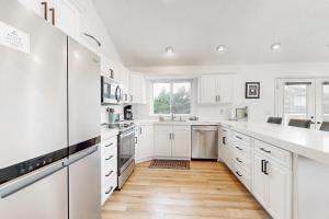 a white kitchen with white cabinets and a wooden floor at The Capella in Pacific City +20 photos