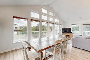 a dining room with a table and chairs and windows at The Capella in Pacific City