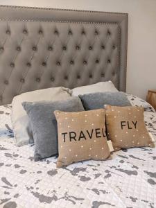 a bed with a headboard and pillows with the words travel fly at Depto en Villa del Parque centro in Buenos Aires