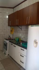uma cozinha com armários brancos e um frigorífico branco em Kit no Centrinho da Lagoa em Florianópolis