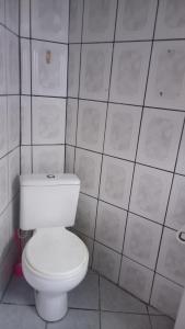 a white toilet in a bathroom with white tiles at Kit no Centrinho da Lagoa in Florianópolis