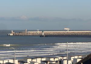 a view of a beach with waves and a pier at Studio Le Mer'Veilleux in Calais