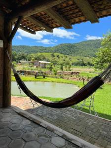 a hammock hanging from a porch overlooking a pond at Recanto Magnata 