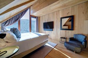 1 dormitorio con 1 cama, 1 silla y 1 ventana en Chalet Enza Baqueira - By EMERALD STAY, en Baqueira Beret