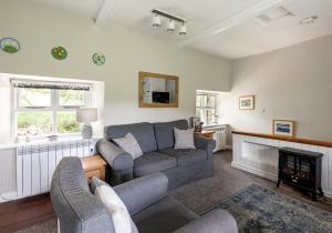 een woonkamer met een bank en een open haard bij Hobsons Cottage in Grinton