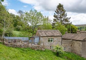 een oud stenen huis op een grasheuvel bij Hobsons Cottage in Grinton