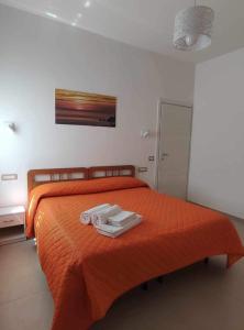 CASA VACANZE CASANOVA في أَجيرولا: غرفة نوم بسرير برتقالي عليه منشفتين