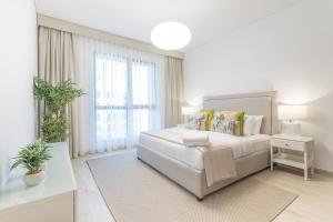 a white bedroom with a bed and a large window at SuperHost - Urban Elegance 2BR in Asayel 2 Near Burj Al Arab in Dubai