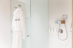 a white robe hanging on a shower door at EVOLUTION Cascais-Estoril Hotel in Estoril
