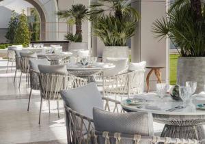 a restaurant with white tables and chairs and plants at One&Only Portonovi in Herceg-Novi