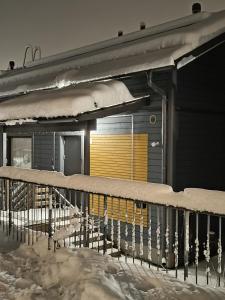 uma cerca coberta de neve ao lado de um edifício em Talo saunalla ja sähköauton oma Type2 latauspiste em Vantaa