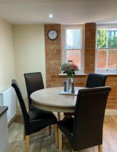 a dining room table with chairs and a clock on the wall at 1 Hatton house 2 bedroom 2 bathroom spacious basement flat in Newark-on-Trent