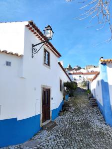 a cobblestone street in a village with blue and white houses at Casa Nº7 - Vila d'Óbidos in Óbidos