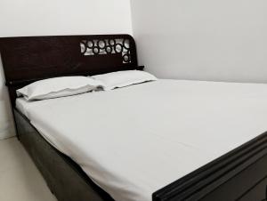 a white bed with two pillows on top of it at Hotel Labbaik Dhanmondi in Dhaka