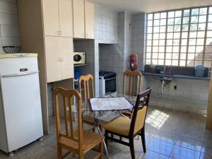 cocina con mesa, sillas y nevera en Solar dos Costais: casa com 4 suítes climatizadas en Uberaba