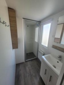 a white bathroom with a sink and a mirror at Super mobil-home aux Sables du Midi in Sérignan