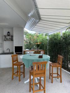 patio con mesa y sillas y cocina en Casa em Riviera de São Lourenço Prática e Confortável, Reformada e Equipada! en Bertioga
