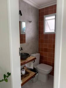 La salle de bains est pourvue de toilettes, d'un lavabo et d'une fenêtre. dans l'établissement Casa em Riviera de São Lourenço Prática e Confortável, Reformada e Equipada!, à Bertioga