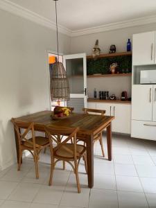 uma cozinha com uma mesa de madeira e cadeiras em Casa em Riviera de São Lourenço Prática e Confortável, Reformada e Equipada! em Bertioga