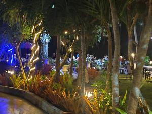 a restaurant with palm trees and people sitting at tables at night at The Wynn Kohjum in Ko Jum