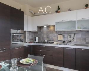 a kitchen with brown cabinets and a glass table at The House on the Lake in Reno Di Leggiuno