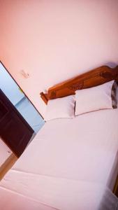 a white bed with a wooden headboard and white pillows at Spacious Two Bedroom at Nyali in Mombasa +21 photos