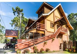 a house with a motorcycle parked in front of it at Pousada Campos Montreal in Campos do Jordão