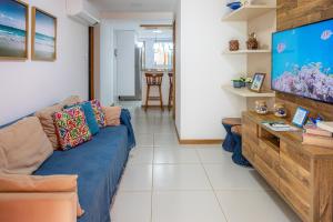 ein Wohnzimmer mit einem Sofa und einem Flachbild-TV in der Unterkunft Village pé na areia na Praia da Espera - Itacimirim in Itacimirim