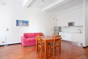 uma cozinha e sala de jantar com uma mesa e um sofá rosa em Casa Terrazzino Bianca em Levanto