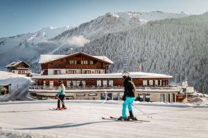 two people on skis in front of a ski lodge at Hotel Birkenhöhe in Hirschegg