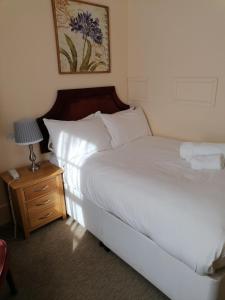 a bedroom with a bed and a night stand with a lamp at The Royal Lion Hotel in Lyme Regis