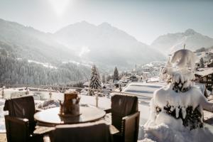 einen schneebedeckten Berg mit einem Tisch und Stühlen in der Unterkunft Hotel Birkenhöhe in Hirschegg