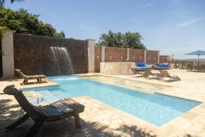 a swimming pool with a fountain and chairs and a table at Pousada La Dolce Vita in Búzios