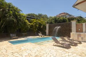 a swimming pool with chairs and a fountain at Pousada La Dolce Vita in Búzios