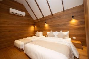 two beds in a room with wooden walls at Ban's Diving Resort SHA Extra Plus in Koh Tao