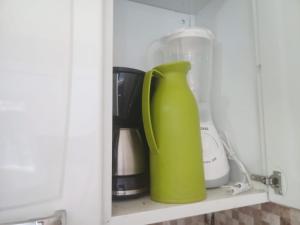 una jarra verde sentada en un estante en un armario en Flat da Natasha, en Arraial do Cabo
