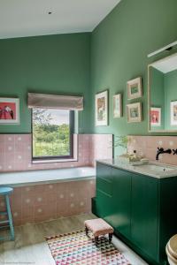 a bathroom with green walls and a sink and a window at Gilboa House in Malmesbury