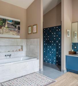 a bathroom with a tub and a tile wall at Gilboa House in Malmesbury