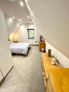 a bedroom with a bed and a desk in a attic at Silvercopse- The Ultimate Oxfordshire Retreat in Kingston Bagpuze