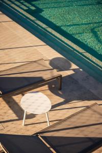 une chaise blanche assise à côté de la piscine dans l'établissement XVI Suites - Adults Only, à Naxxar
