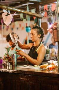 a woman standing at a counter drinking from a glass at Indiana Kite school and Hostel in Cumbuco