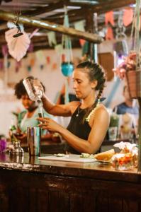 une femme debout au comptoir buvant à partir d'un verre dans l'établissement Indiana Kite school and Hostel, à Cumbuco